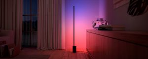 A Philips Hue Signe gradient floor lamp available in the Black Friday lighting sale washes a wall in pink and blue tones of smart light.