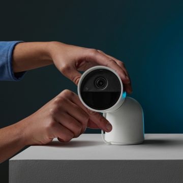 Hands adjusting a white Secure camera wtih desktop stand