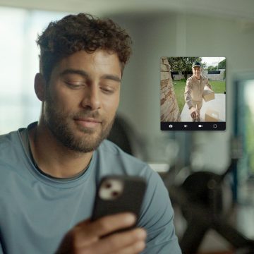 Eine Person sieht auf dem Mobiltelefon über die Hue App einen Lieferanten an ihrer Haustür.