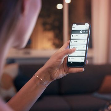 Frau hält Telefon mit Smart-Light-App in der Hand