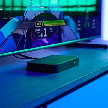 An HDMI Sync box 8K sits on a TV console in a room with blue entertainment lighting.