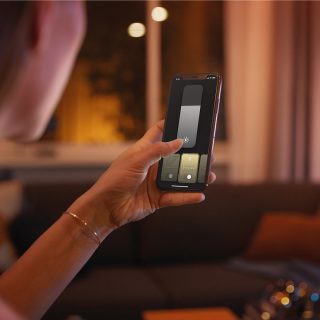 A person controlling Philips Hu smart lighting using the Hue app on a smart phone.
