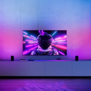 Two play wall washer lights placed each side of TV and glowing in vibrant pink and blue smart light.