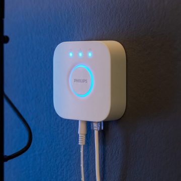 The Hue Bridge device hangs on a blue-colored wall.