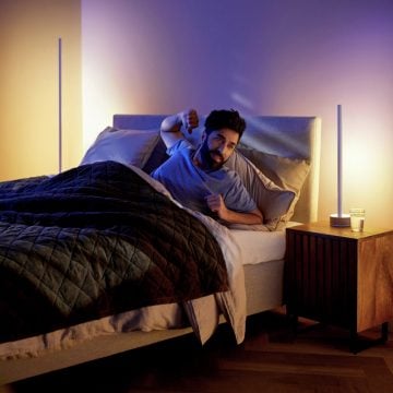 Man waking up in bed with two smart LED lamps mimicking a sunrise