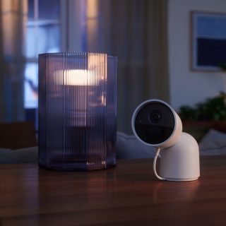 Smart home security camera on table next to smart lamp