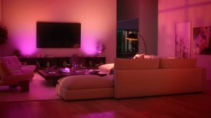 A living room TV area with walls washed in pink and purple tones of smart light