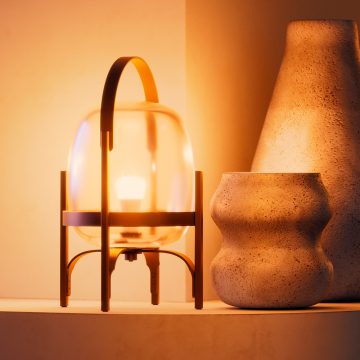An A19 smart bulb fitted to a glass table lamps glowing in a warm tone of white smart light