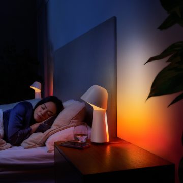 Woman sleeping in bed with bedside lamp dimly lit to red and orange smart light