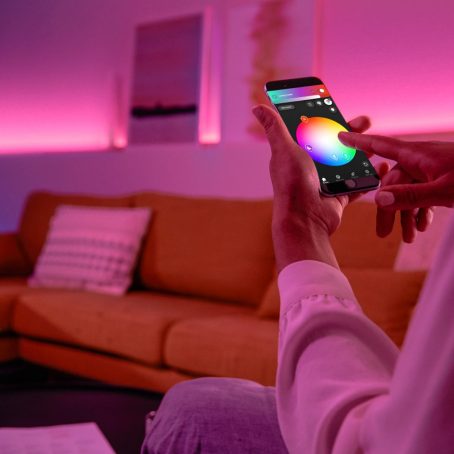 Hand tapping smartphone to adjust light color in Hue app 