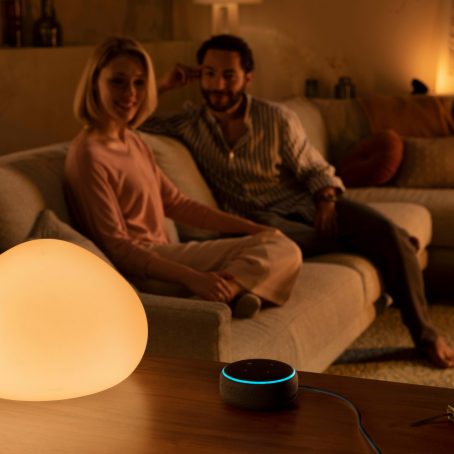 Couple on couch next to smart home assistant in living room