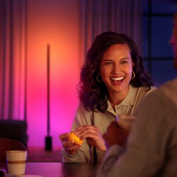 Smiling woman seated at table with gradient LED lamp behind her
