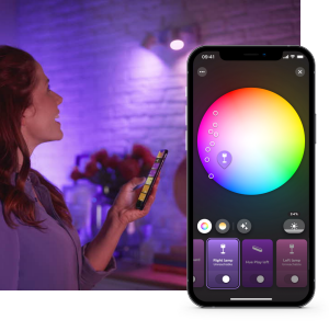 Person adjusting smart lighting color using a mobile app in a living room with purple light illuminating the wall.