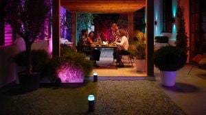 Four adults seated at outdoor dining table with purple and blue landscape lighting 