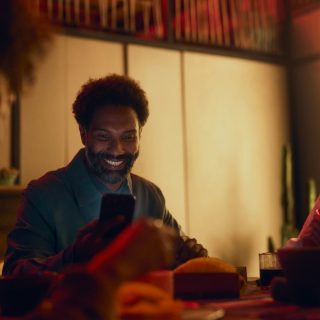 Smiling man checks his smart home security system on smartphone