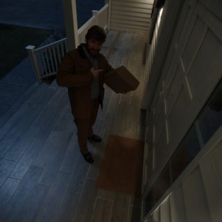 Person delivering a package at a front door under porch lighting, with illuminated entryway supporting visibility and security.
