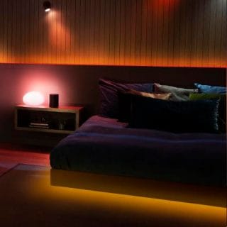 Gradient lightstrip emits a soft ambient glow along a bedroom wall and bed frame, creating a relaxing evening scene.