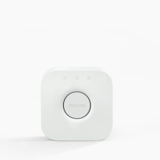 White square smart lighting hub with rounded edges, matte finish, central circular button, and three icons above the button.
