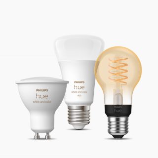 A set of smart light bulbs in various shapes and finishes, featuring white and color lighting, with visible product labels.
