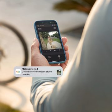 A person receives a motion detection notification and monitors their front door via the Hue app. while away from home 