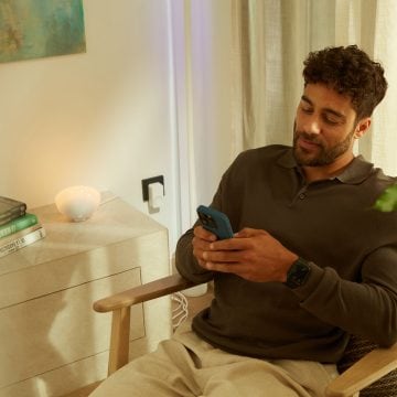 A man controls his doorbell, chime, and Philips Hue lights via the Hue app on his smartphone. 