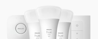 A collection of white smart light bulbs, a hub, and a remote control, all part of a smart lighting starter kit set.