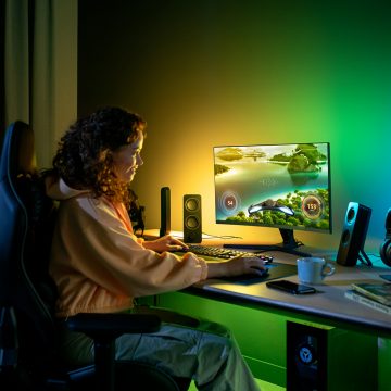 Femme assise à son bureau gaming avec éclairage connecté Philips Hue vert et jaune