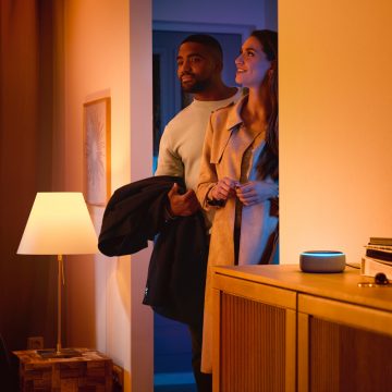 Homme et femme entrant dans une maison avec un haut-parleur intelligent 