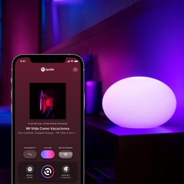 Une lampe connectée sur une table d'appoint avec un appareil mobile affichant l'onglet Sync dans l'application Hue