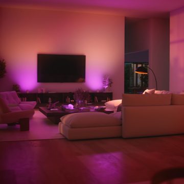 Un salon est éclairé dans les tons roses et violets par la lumière connectée projetée par le Hue Play wall washer.