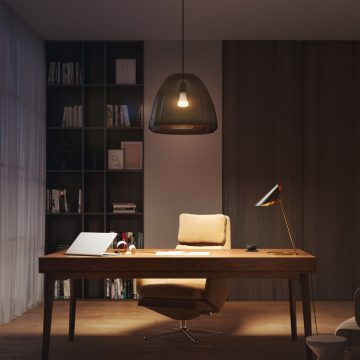 Een kantoorplek thuis met bureau en stoel, verlicht met een slimme tafellamp en een hanglamp, die zijn ingesteld op warme, zachte tinten.