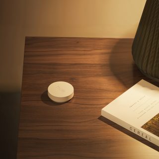Een witte Philips Hue smart button op een tafel naast een laptop.