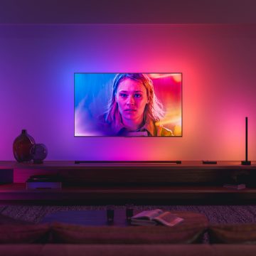 En TV som er synkronisert med Philips Hue surroundbelysning, lyser i blå, rosa og røde lystoner som matcher bildet på skjermen.
