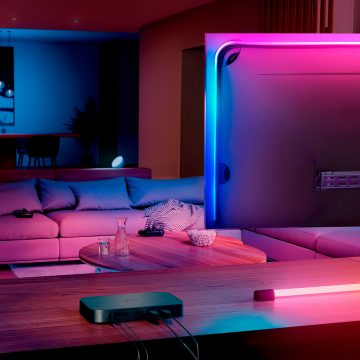 En Hue sync box 8K som står på en spillkonsoll ved siden av en TV-skjerm i en stue.