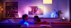 En mann og en kvinne som sitter på en sofa foran LG-TV med lilla og blå Hue-belysning