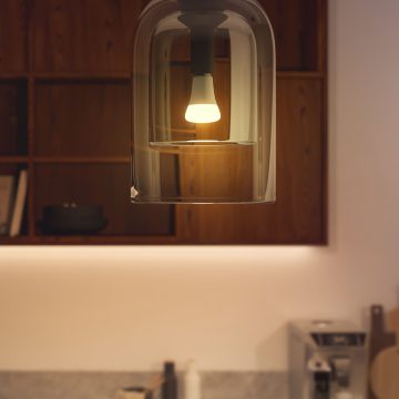 Uma lâmpada inteligente Hue a brilhar numa luz regulável branca quente.